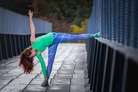 Athlete woman streching. Fitness model mother exercising in urban city location.の写真素材