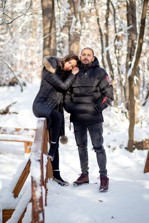 Man and woman in love holding hands on a bridge. Snowy winter background.の写真素材