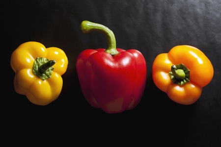 Three colored peppers set on a black backgroundの写真素材