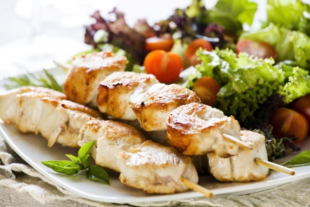 Close up photograph of three chicken skewers served with saladの写真素材