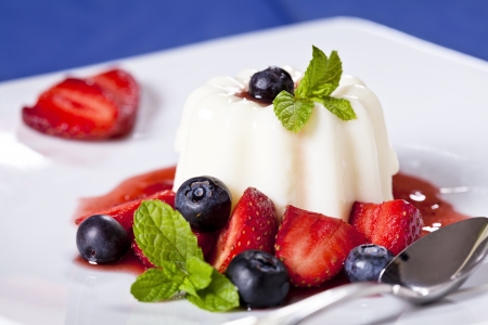 Close up photograph of a panna cotta dessert with strawberries and blueberriesの写真素材