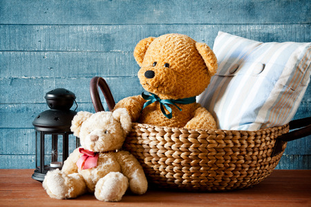 Cute teddy bear in a basket on a wooden tableの写真素材