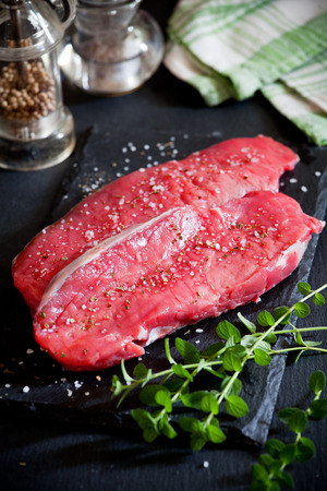 Two rib eye steaks on a slate plate with spicesの写真素材