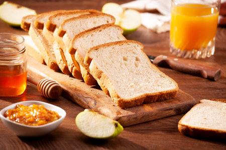Slices of loaf bread for breakfast with jam and juiceの写真素材