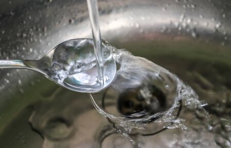 Running water out of a water tap in a metallic kitchen sinkの写真素材
