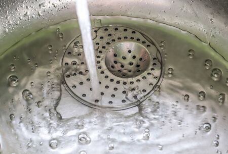 Running water out of a water tap in a metallic kitchen sink