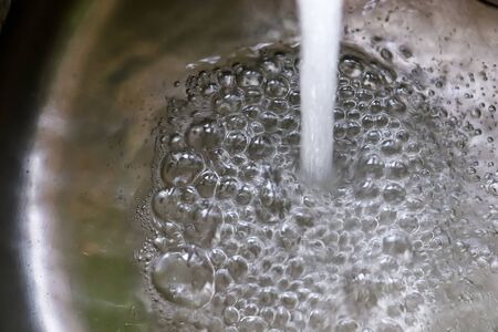 Running water out of a water tap in a metallic kitchen sink