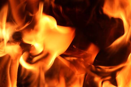 Close up on a crackling warm camp fire burning with red and orange flames