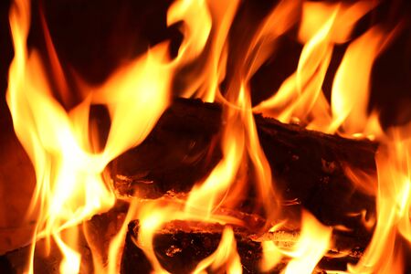 Close up on a crackling warm camp fire burning with red and orange flames