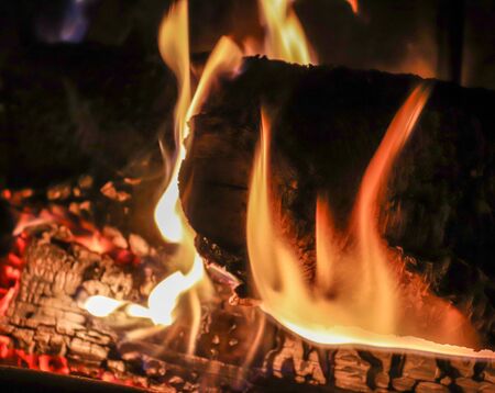 Close up on a crackling warm camp fire burning with red and orange flames