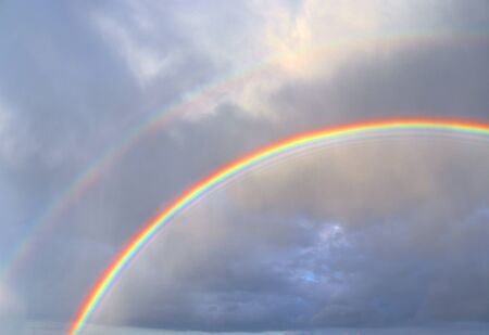 Stunning natural double rainbows plus supernumerary bows seen at a lake in northern germanyの写真素材