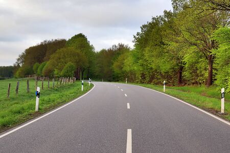 Empty country roads found in northern europe with surrounding fields and trees