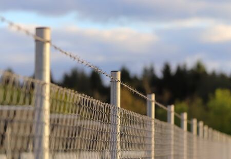 Close up view on barbed wire on a field with a soft bokeh in the backgroundの写真素材
