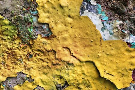 Detailed and colorful close up at cracked and peeling paint on concrete wall textures in high...