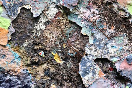 Detailed and colorful close up at cracked and peeling paint on concrete wall textures in high resolutionの写真素材