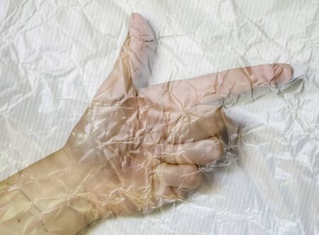 Hand of a young female wrapped in plastic film showing different symbolsの写真素材