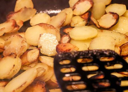 Close up view on fried potatoes during cookingの写真素材
