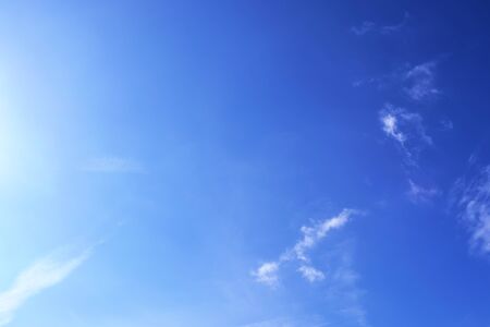 Beautiful view at bright sunbeams with some lens flares and clouds in a blue skyの写真素材