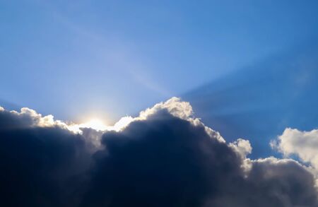 Beautiful view at bright sunbeams with some lens flares and clouds in a blue sky