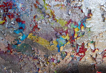 Detailed and colorful close up at cracked and peeling paint on concrete wall textures in high resolution.の写真素材