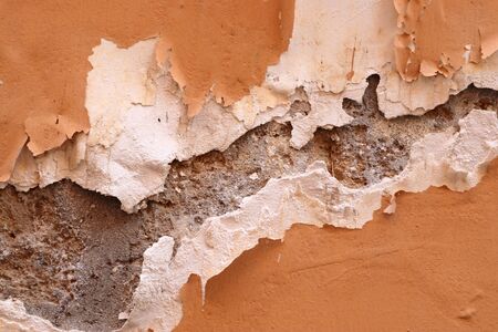 Detailed and colorful close up at cracked and peeling paint on concrete wall textures in high resolution.の写真素材