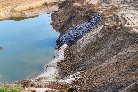 View into a gravel pit with piles of sand and tire tracks