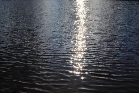 Detailed close up view on water surfaces with waves and ripples and the sunlight reflecting at the...