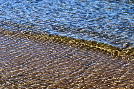 Detailed close up view on water surfaces with waves and ripples and the sunlight reflecting at the...
