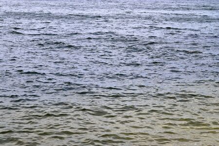 Detailed close up view on water surfaces with waves and ripples and the sunlight reflecting at the...