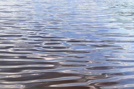 Detailed close up view on water surfaces with waves and ripples and the sunlight reflecting at the...