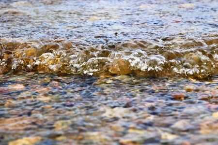 Detailed close up view on water surfaces with waves and ripples and the sunlight reflecting at the surfaceの写真素材