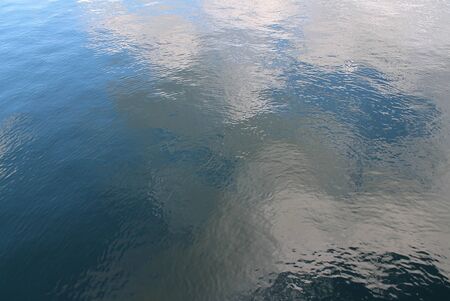 Detailed close up view on water surfaces with waves and ripples and the sunlight reflecting at the...