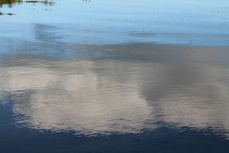 Detailed close up view on water surfaces with waves and ripples and the sunlight reflecting at the surfaceの写真素材