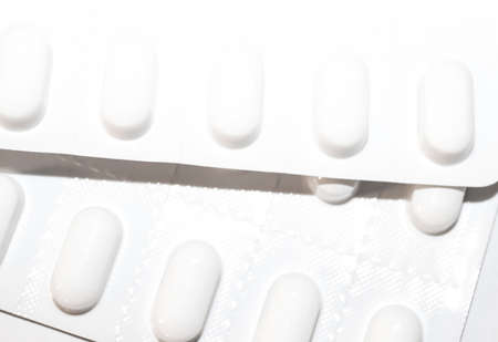Packs of white pills packed in blisters with copy space isolated on a white background. Focus on...