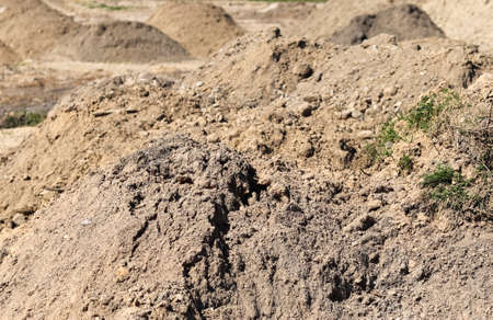 View into a gravel pit with piles of sand and tire tracks