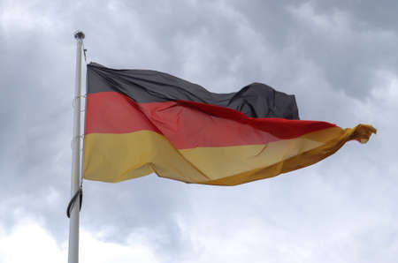 Germany flag at a flagpole moving in the wind against the skyの写真素材