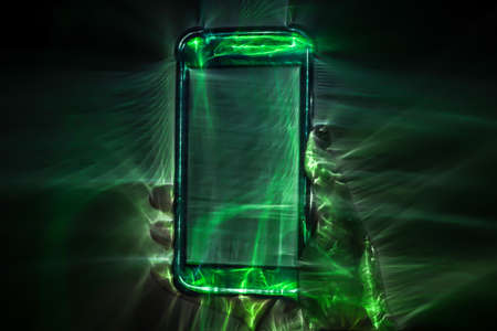 3D-Illustration of a female hand holding a smartphone with kirlian glowの写真素材