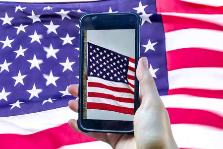USA flag in a smartphone display in front of a big USA flagの写真素材