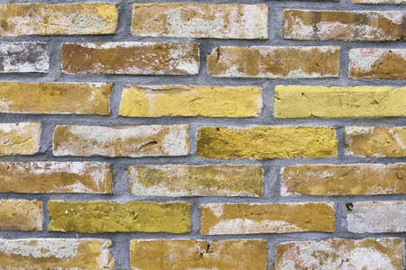 Detailed view at a colorful old and weathered brick wall texture. Panoramic background.