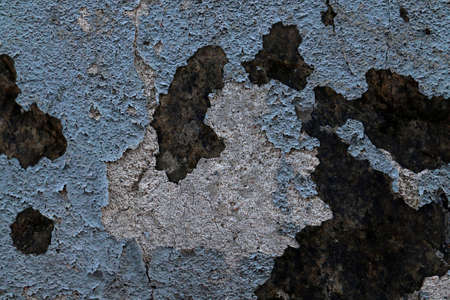 Detailed and colorful close up at cracked and peeling paint on concrete wall textures in high...