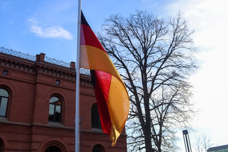 German flag at a flagpole moving in the wind against the skyの写真素材