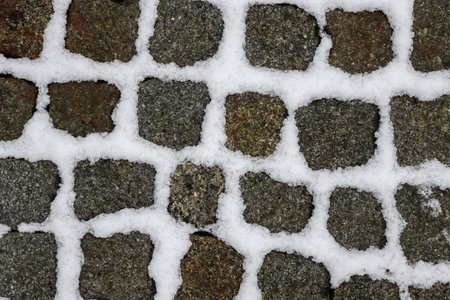 Surface of white snow on an old cobblestone way in winterの写真素材