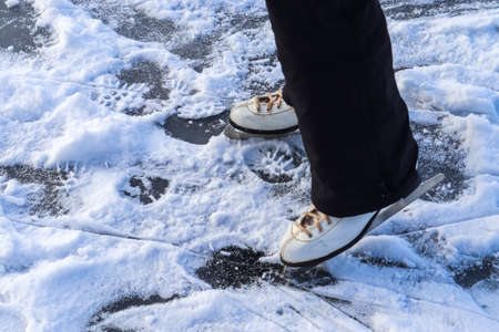 Close up on womans feet wearing ice skating boots and standing on iceの写真素材