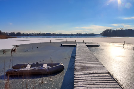 Snow covered wooden jetty at a frozen lake on a sunny day in germanyの写真素材