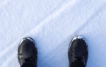 High angle view at black boots standing in fresh snowの写真素材