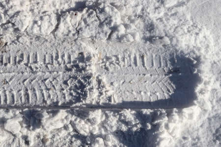 Tire Tracks on snow covered streets in a close up viewの写真素材