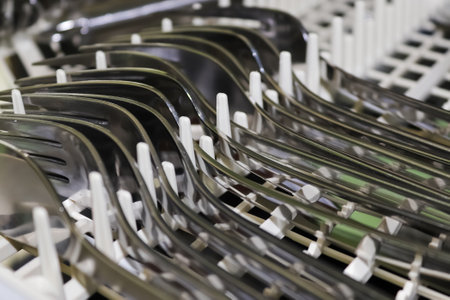 Selective focus close up on dishes and cutlery on dishwashing machine. Fresh and clean dishes