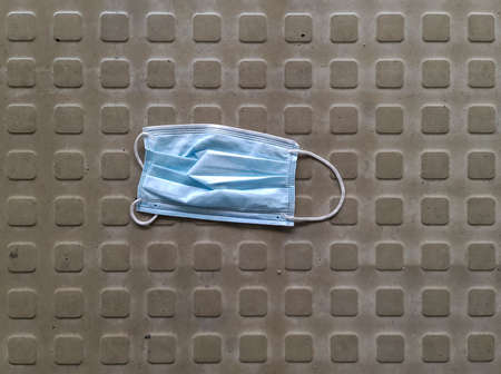 Close-up image of a surgical mask dropped and abandoned in the street during the virus crisisの写真素材