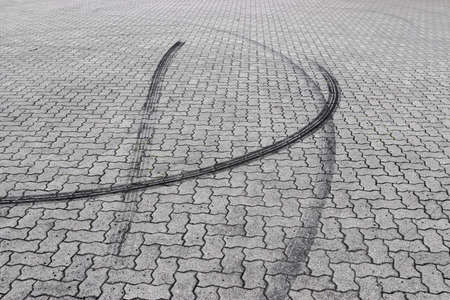 Black tire tracks on a cobblestone roadの写真素材