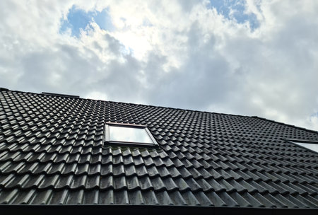 Open roof window in velux style with surrounding black roof tilesの写真素材